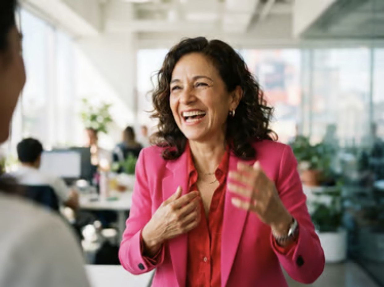 A woman in a fuchsia blazer mid-sentence, lighting up the room around her
