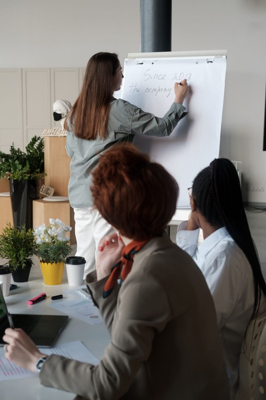 A woman at a flip chart, leading a small workshop